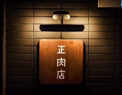 바른고기 정육점 강남점 — 어두운 벽돌 벽에 조명을 받고 걸린 正肉店 원목 간판